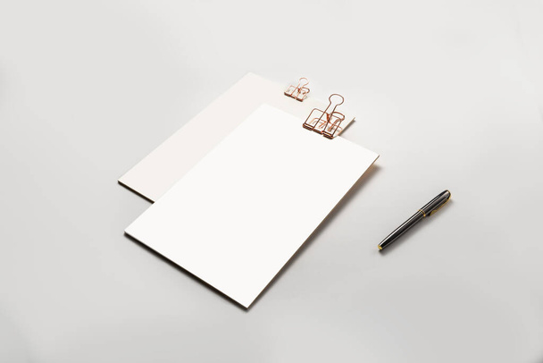 Кліпборд із золотим кліпом, порожніми аркушами паперу та ручкою на білому тлі. Шаблон для фірмового стилю. мінімальний макет концепції шаблону
. - Фото, зображення
