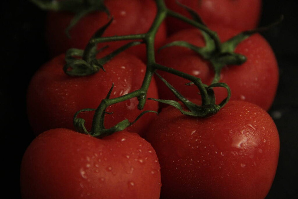 red, fresh and organic tomatoes on a black background - Φωτογραφία, εικόνα