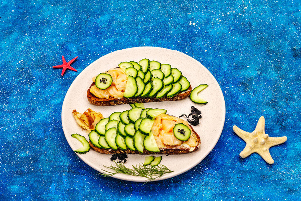 Funny salmon sandwiches with cucumber for kids. Healthy lunch, nautical background - Photo, Image