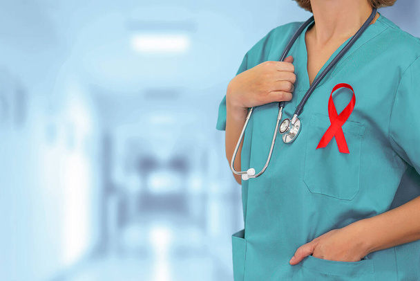 Chirurgo donna con stetoscopio con nastro rosso HIV in piedi su sfondo sfocato della clinica corridoio. - Foto, immagini