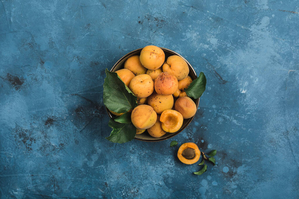 Fresh apricots in a bowl on a light blue background. Top view. Copy space. Horizontal orientation. - Photo, Image