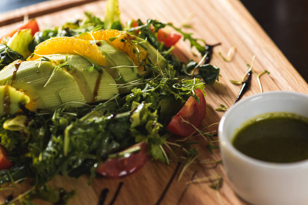 Свежий овощной салат с кусочками мяса на деревянном подносе на темном фоне
 - Фото, изображение
