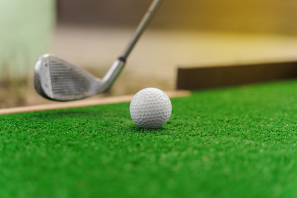 Close-up gra w mini-golfa na zielonej trawie przy użyciu niblick. Gracz uderza białą piłkę. Gra w golfa. Ogłoszenie o klubie golfowym - Zdjęcie, obraz