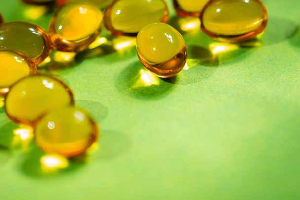 vitaminas en cápsulas son de color amarillo sobre un fondo verde.close up.el concepto de deficiencia de vitaminas y minerales para la salud del cuerpo.espacio para el texto
. - Foto, imagen