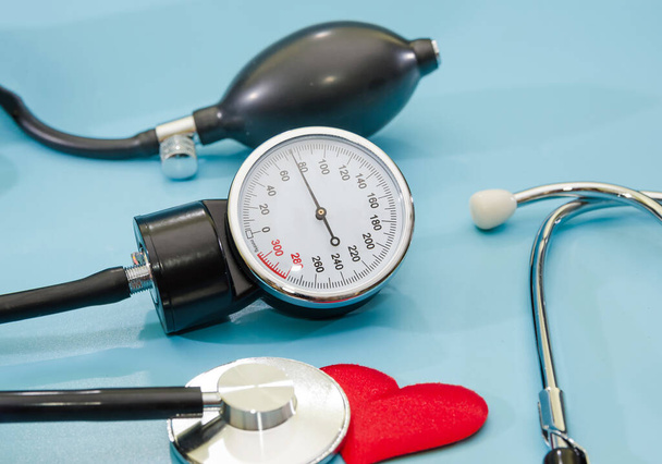 Schwarzes Blutdruckmessgerät und Herz isoliert auf blauem Hintergrund. Das Konzept der Gesundheit, die Messung von Druck, Herzkrankheiten - Foto, Bild