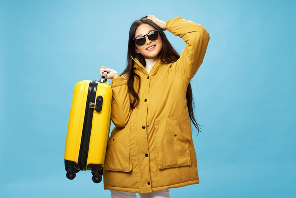 Dívka v teplém saku se žlutým kufříkem se usmívá do kamery  - Fotografie, Obrázek