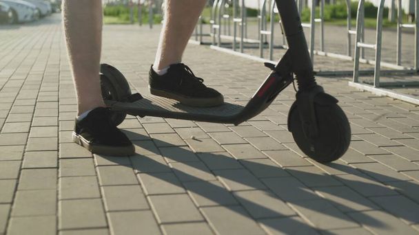 Şortlu çekici bir adam elektrikli scooterıyla yürüyor. - Fotoğraf, Görsel