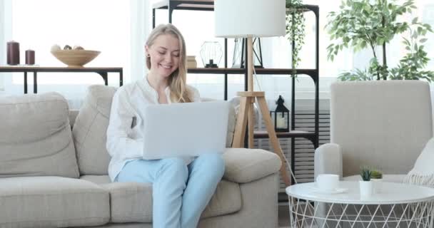 Happy woman using laptop on sofa at home - Video