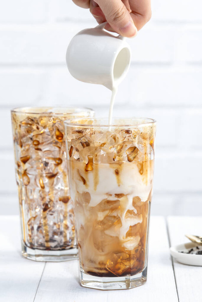 Making bubble tea, pouring blend milk tea into brown sugar pattern drinking glass cup on white wooden table background, close up, copy space - Foto, afbeelding
