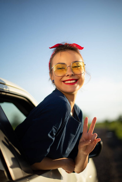道路の旅で車の女性の幸せの窓の外に笑みを浮かべて手を振っ. - 写真・画像