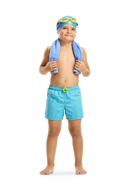Full length portrait of a smiling boy in swimsuit and cap holding towel isolated on white background - Foto, Imagem
