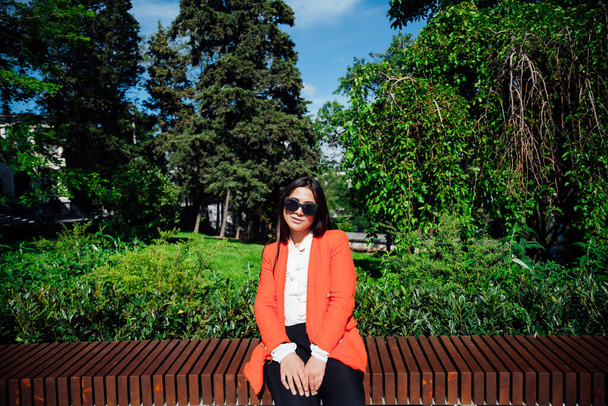 mooie aziatische vrouw brunette in rood business pak op de straat - Foto, afbeelding