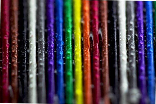 Heldere plastic strips van regenboog kleur met waterdruppels. Kleurrijke achtergrond.Close-up in macro-modus. - Foto, afbeelding