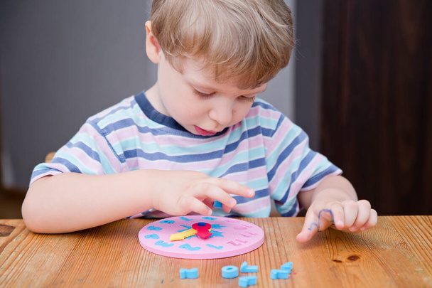 小さな男の子は時計のおもちゃで時間を学びます,時間を伝えるために子供の学習,幼児の発達のために遊ぶことによって学習の概念. - 写真・画像