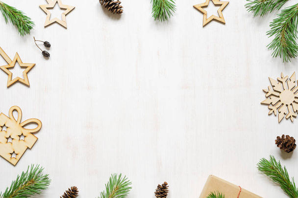 Christmas tree branches, cones and wooden Christmas accessories on a white wooden background. Frame. Copy space composition - Foto, Imagem