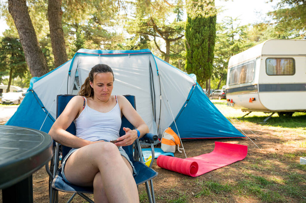 Woman wearing white shirt enjoying holidays infront of camping tent in a resort. - Photo, Image