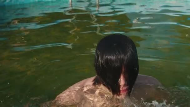 Молодой человек выпрыгивает из воды и удаляет волосы с лица
 - Кадры, видео