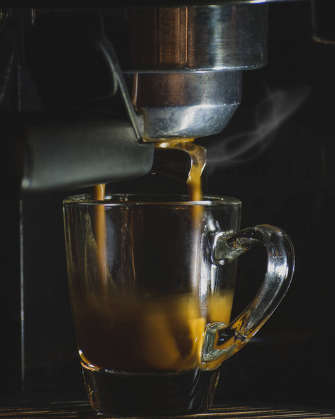Espresso glass cup in machine, hot coffee brewing - Foto, Bild