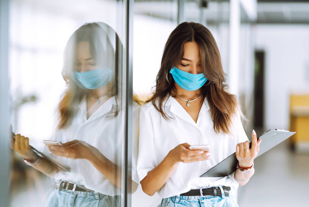 Portrait of young business woman in protective face mask at office. COVID - 19 virus protection. - Valokuva, kuva