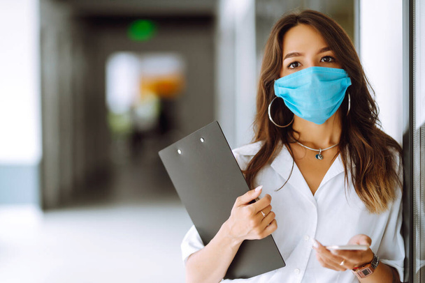Portrait of young business woman in protective face mask at office. COVID - 19 virus protection. - Foto, Imagem