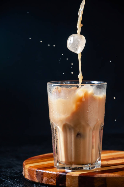 Iced Coffee with Splash and Ice Cube in Tall Glass on Dark Background. Concept Refreshing Summer Drink - Zdjęcie, obraz