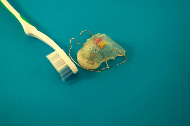 Zahnkorrekturplatte und Zahnbürste in der linken oberen Ecke auf blauem Hintergrund  - Foto, Bild