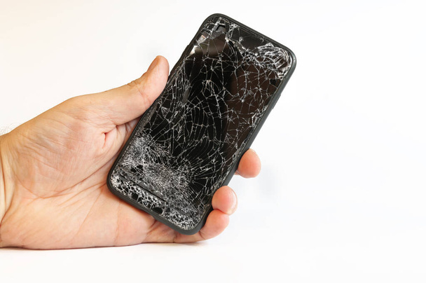 Modern smartphone with highly broken screen in men hand on white background - Photo, Image