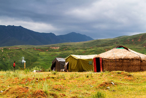Yurts and tents in Tian Shan mountains near Pamir Highway in Kyrgyzstan, Central Asia - Photo, Image