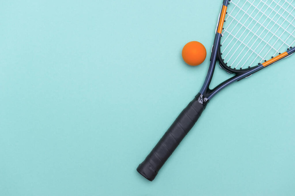 Gros plan d'une balle de squash et d'une raquette sur fond bleu. Concept de sport individuel. - Photo, image
