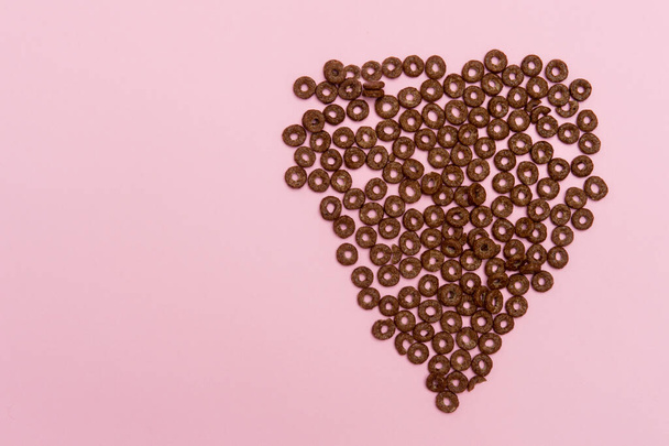 Magas látószögű kilátás szív alakú csokoládé karika ellen rózsaszín háttér - Fotó, kép
