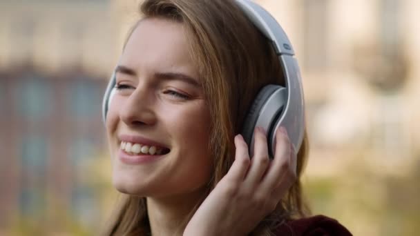 Mujer feliz escuchando auriculares de música al aire libre. Sonriente chica bailando en la calle
. - Metraje, vídeo