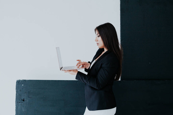 Bella donna bruna in bianco e nero business vestiti in ufficio con un computer portatile - Foto, immagini