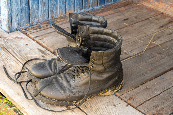 Köy evinin verandasında eski deri yürüyüş botları. Yaz bir seyahat zamanıdır. Kapat. - Fotoğraf, Görsel