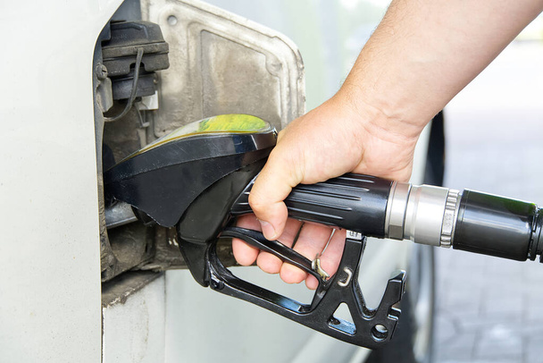 Egy férfi dízellel tölti meg az autót. Fekete olajadagoló a benzinkútnál. A régi kisbusz feltöltése3 dízelolajjal en90. - Fotó, kép