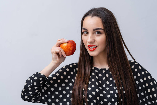 Beauty model girl posing with apple on white background. Pretty girl looks to the camera. - Zdjęcie, obraz