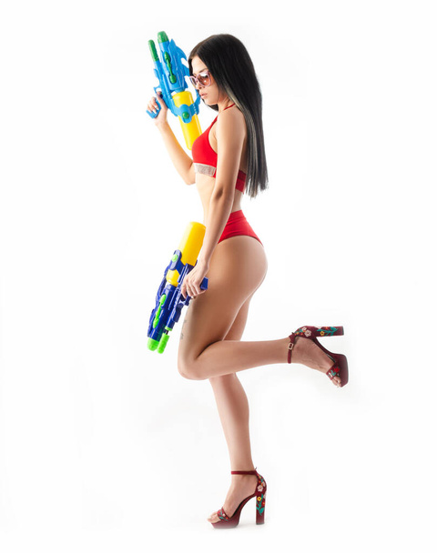 брюнетка дівчина з водяним пістолетом в червоному купальнику, струнка і сексуальна
 - Фото, зображення
