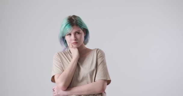 Ungeduldige und gelangweilte Frau mit gefärbten Haaren vor weißem Hintergrund - Filmmaterial, Video