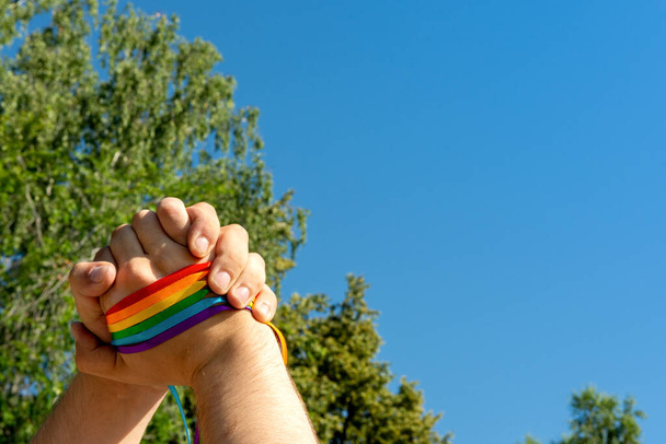 Gay pride concept. Hand making sign of friendship and equality with gay pride LGBT rainbow flag wristband - Zdjęcie, obraz