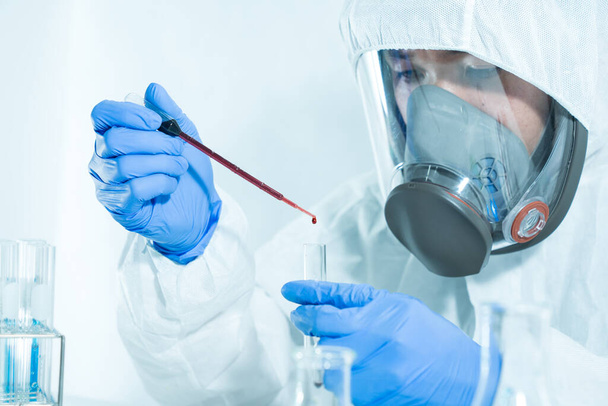 Os cientistas estão a derramar sangue num tubo de vidro num laboratório de ciências para procurar um vírus.
. - Foto, Imagem