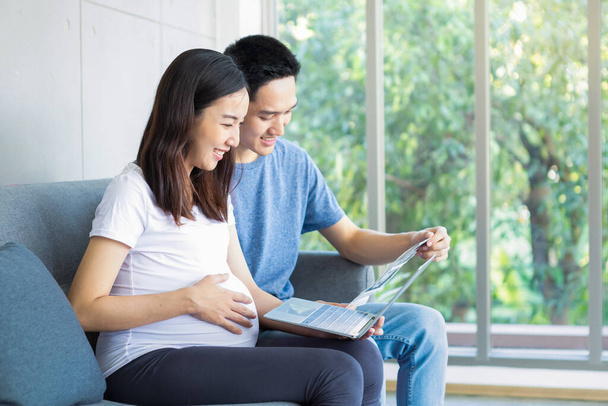 Pregnant concept. Happy couple show the scan of their baby and laptop. father and mother are holding the baby ultrasound photo. - Photo, Image