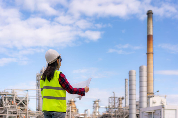 Asian woman engineer work control at power plant energy industry manufacturing oil refinery. Engineering check plant with blueprint. - Foto, imagen
