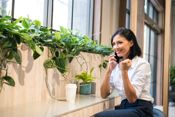 Co working space concept. A young woman is working in a common area. Women are using mobile phones to contact work. Show pleasure with the business deal. - Photo, Image