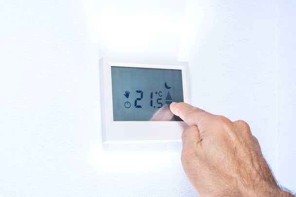 hand pressing on a touch screen of a thermostat adjusting the temperature - Photo, Image