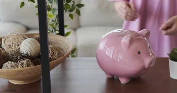 Woman inserting coin into piggy bank - Footage, Video
