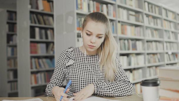 Pretty teenage girl writes a letter in notebook at library closeup - Foto, immagini