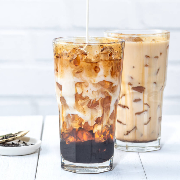 Making bubble tea, pouring blend milk tea into brown sugar pattern drinking glass cup on white wooden table background, close up, copy space - Φωτογραφία, εικόνα