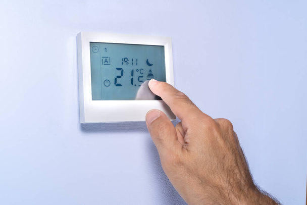 pulsación manual en una pantalla táctil de un termostato que ajusta la temperatura
 - Foto, imagen
