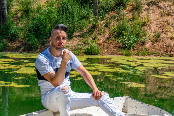 Jovem de calças brancas e estilo moderno posando na lagoa de água doce de Clot De La Mare De Deu em Burriana. Conceito de moda
 - Foto, Imagem