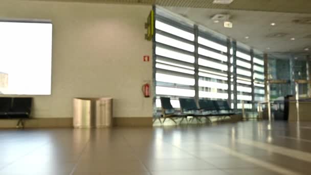 Uluslararası havaalanı. İş adamları yük arabalarını çekiyor. Terminal turistleri geliyor ve lobide yürüyor. - Video, Çekim