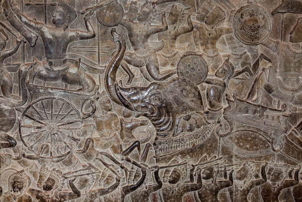 bajorrelieves en las paredes de la galería exterior en Angkor Wat el batido del océano de leche o batallas entre devas y asuras.At Angkor Wat, la pared de la galería externa está cubierta con unos 12.000 o 13.000 metros cuadrados - Foto, Imagen